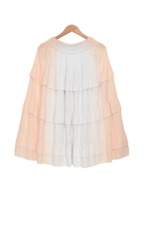 A white tiered maxi skirt with a smocked waistband hanging on a wooden hanger, photographed against a white background. The skirt features five ruffled layers and a flowy silhouette.